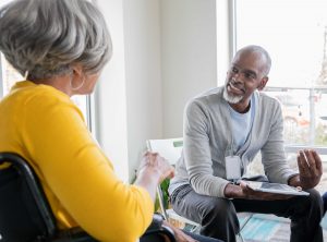 Black Male Social Worker talking with older female client.