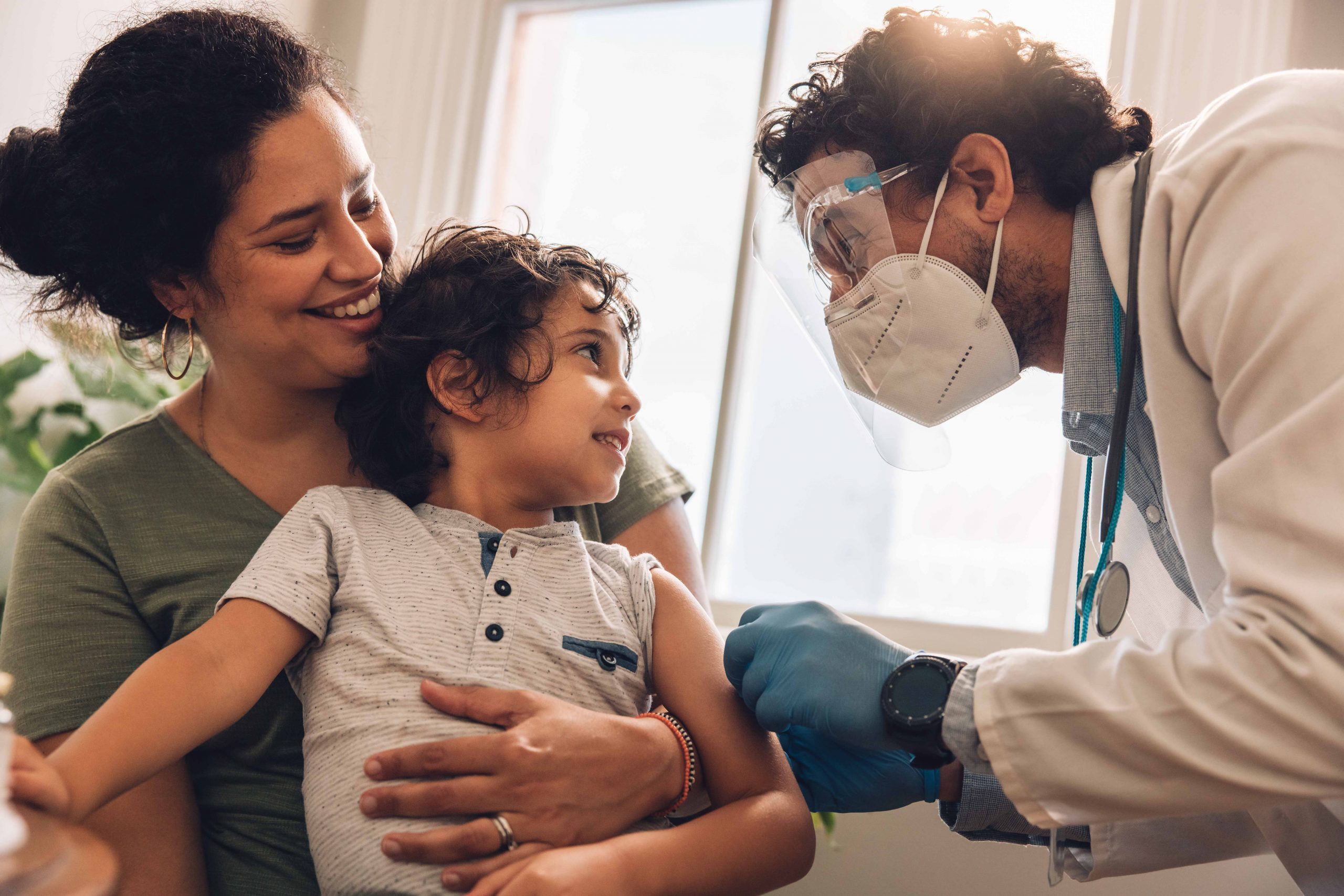 Mother with child getting a COVID-19 vaccination from male health care provider.